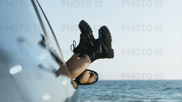 Woman s feet out car window near sea