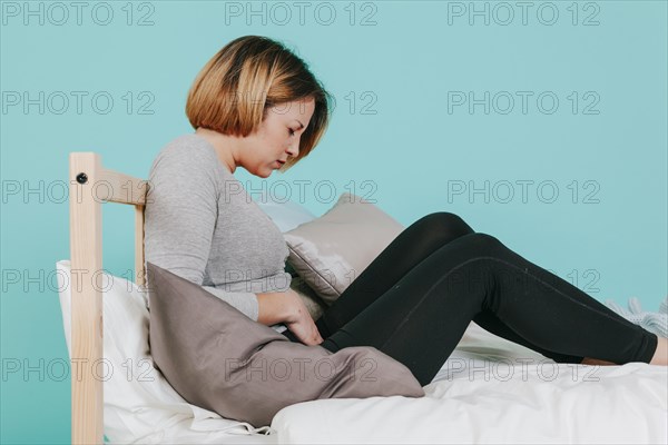 Woman touching hurting belly bed