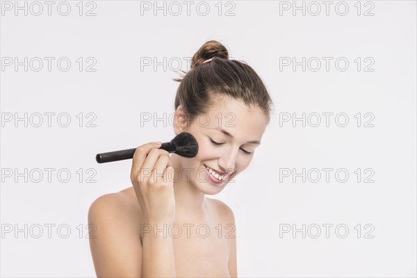 Woman with bare shoulders using powder brush