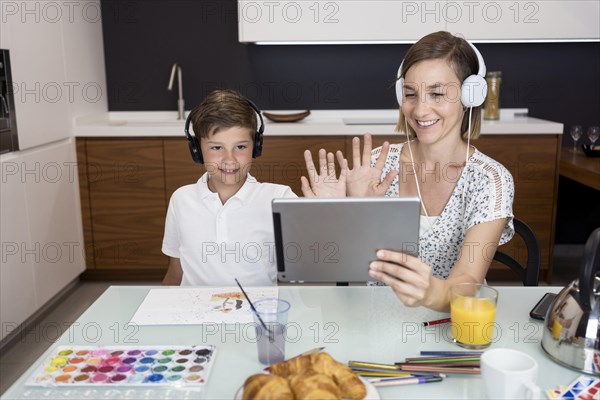 Young boy doing video conference together with mother