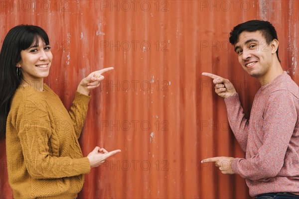 Young couple pointing orange fence