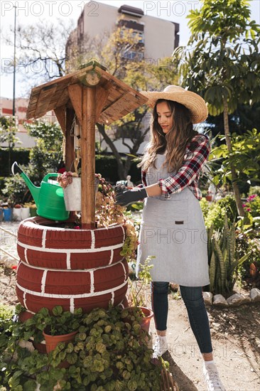 Young female gardener taking care plant handmade well