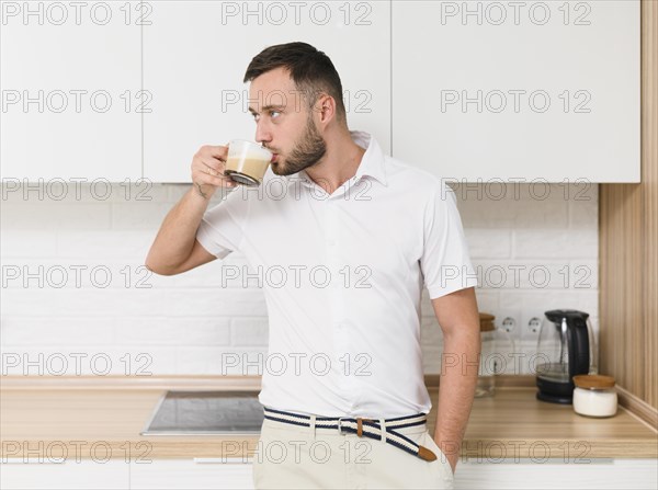 Young man tshirt sipping coffee kitchen