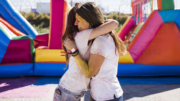 Young women embracing each other celebrating holi festival