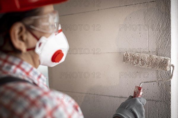 Back view female construction worker with helmet paint roller