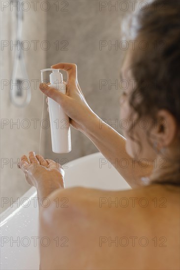 Back view woman bathtub with lotion