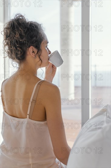 Back view woman pijama drinking coffee