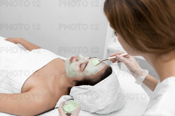 Beautician applying face mask female client 5