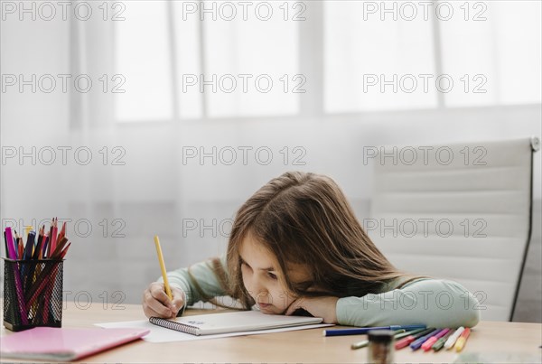 Bored little girl taking notes