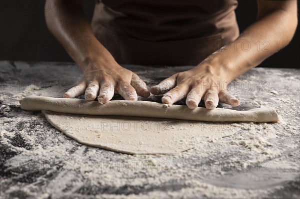 Chef rolling dough with lot flour table