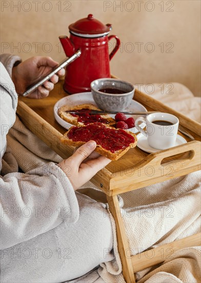 Close up hand holding bread slice with jam