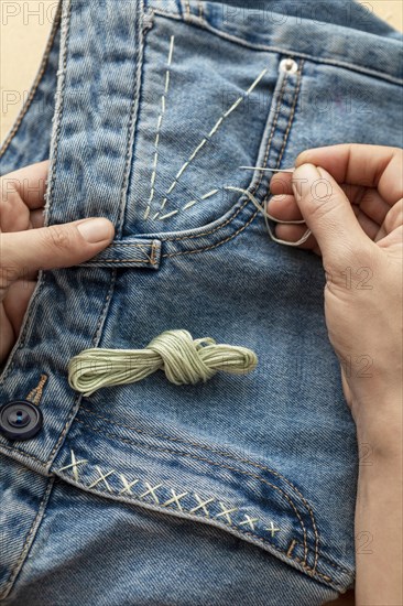 Close up hand sewing jeans