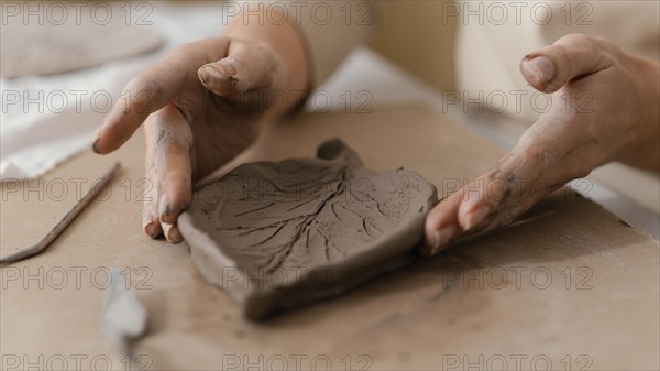 Close up hands holding clay leaf