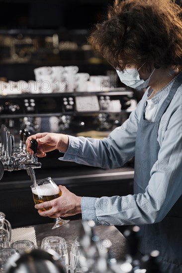 Close up man with mask pouring beer