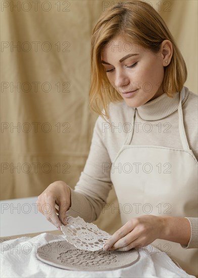 Close up woman decorating clay plate