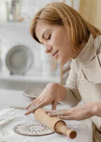 Close up woman using rolling pin pottery