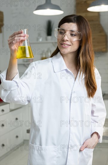 Front view female scientist with safety glasses holding test tube