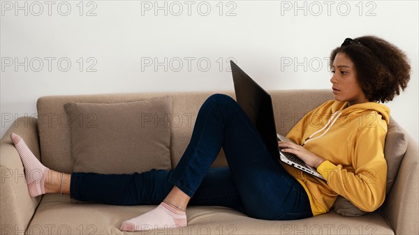 Full shot girl couch with laptop