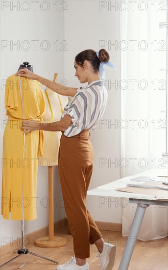 Full shot woman measuring dress