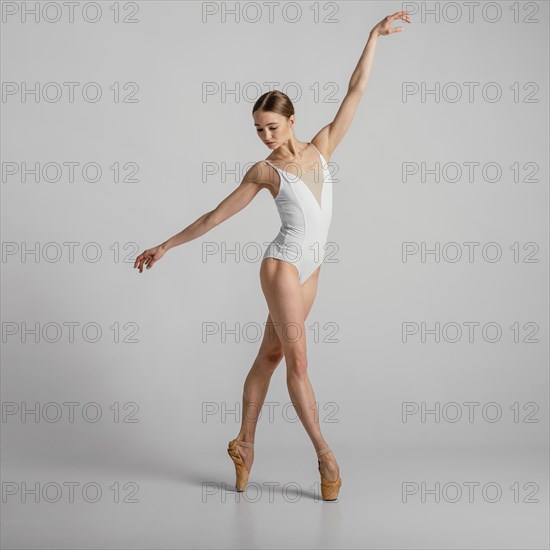 Full shot woman standing pointe shoes