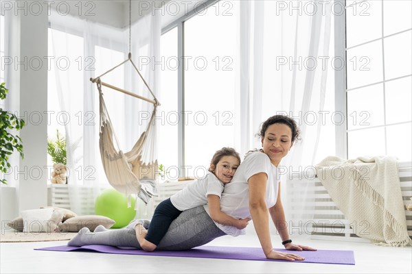 Full shot woman stretching with kid 2