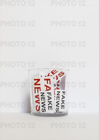 Glass with paper sheet with fake news