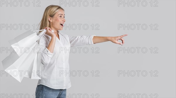 Happy woman holding shopping bags pointing possible store sale