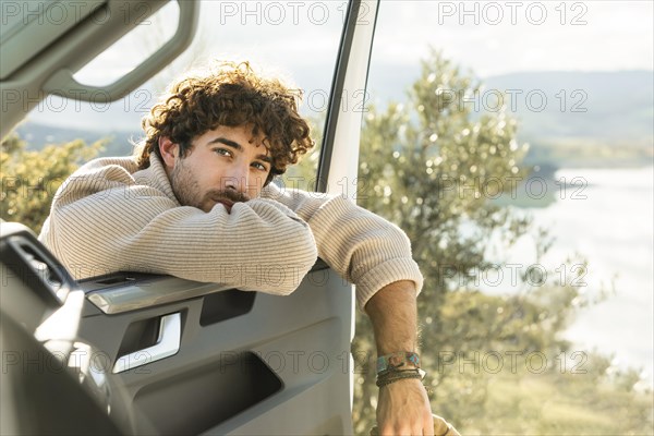 Man posing with car door while road trip