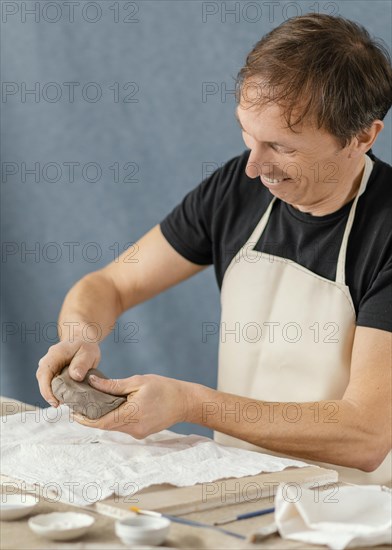 Medium shot man doing pottery home