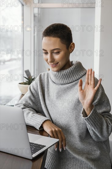 Medium shot woman waving laptop