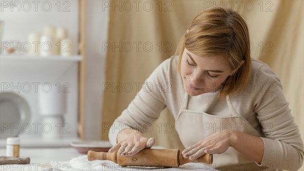 Medium shot woman with rolling pin