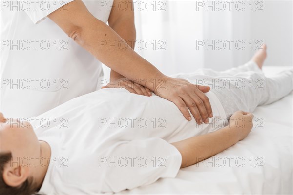 Osteopathist treating kid by massaging his body
