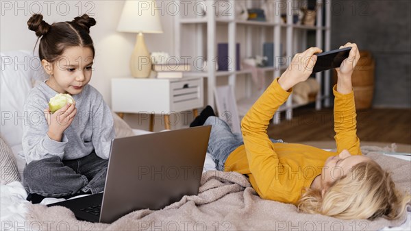 Siblings bed watching video laptop mobile