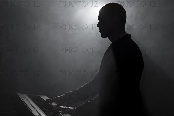 Side view artist playing piano smoke shadows effects