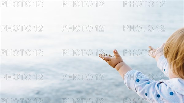 Side view baby enjoying water view with sand hands