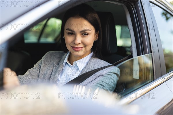 Smiley businesswoman driving her car looking side mirror