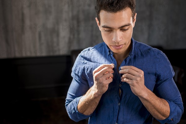 Portrait man buttoning his blue shirt