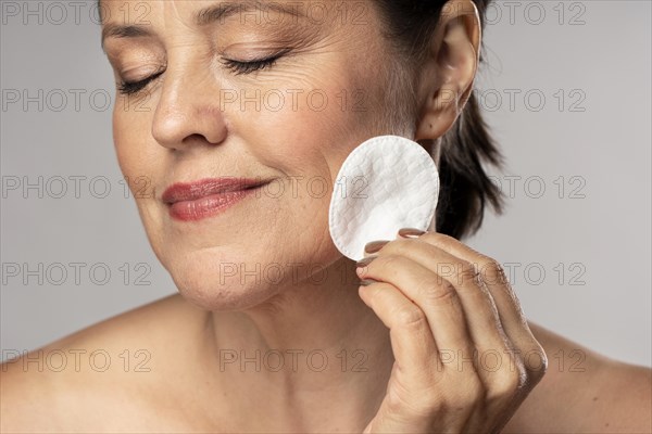 Smiley elder woman using cotton pad make up removal