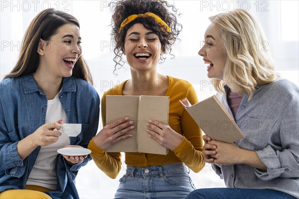 Three women laughing together with book