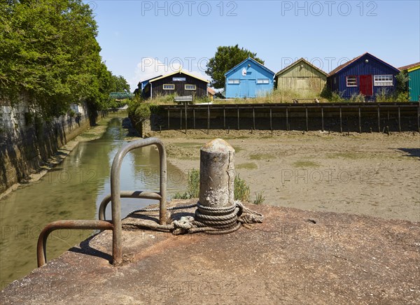 Colourful houses and a jetty with bollards at low tide in Le Chateau-d'Oleron