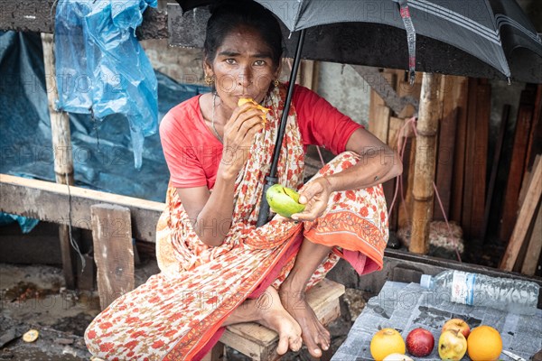 Woman eating a mango in front of her house