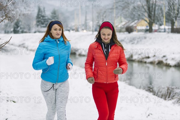 Smiling two female friends jogging winter season