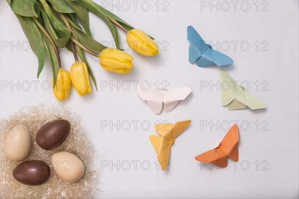 Spring composition with chocolate eggs tulips paper butterflies