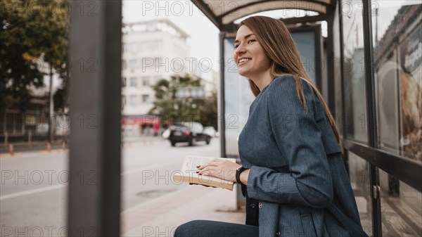 Woman waiting bus holding book
