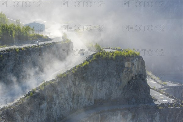 Trucks driving in dusty porphyry quarry