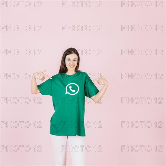 Portrait smiling woman pointing her t shirt with whatsapp icon