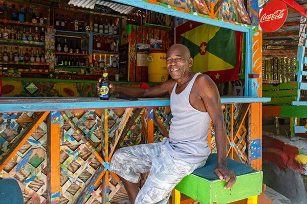 Local black man drinking Carib beer at Charlie's Bar on Happy Hill
