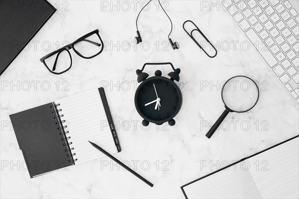 Pencil diary eyeglasses earphone paperclip magnifying glasses alarm clock with keyboard diary white desk