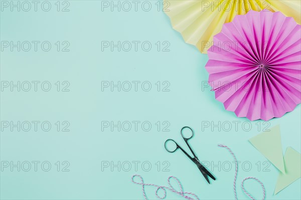 Pink yellow paper fans with scissor thread teal background