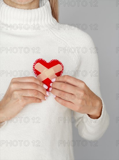 Woman holding heart with band aids